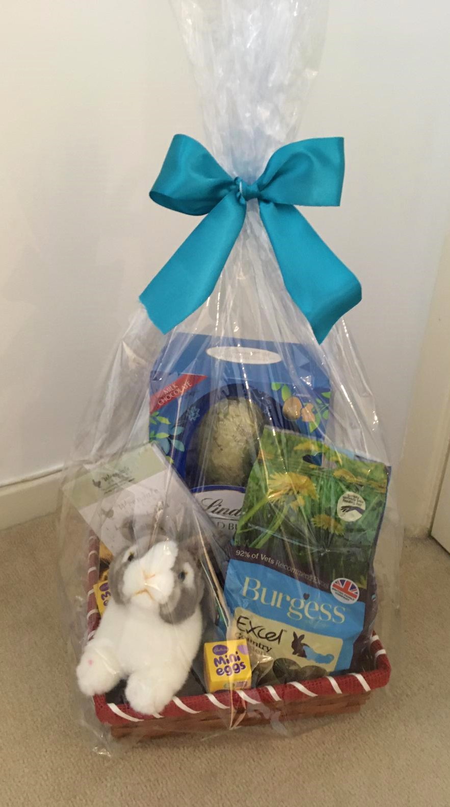 A picture of a hamper containing a toy rabbit, easter egg and other bunny related prizes