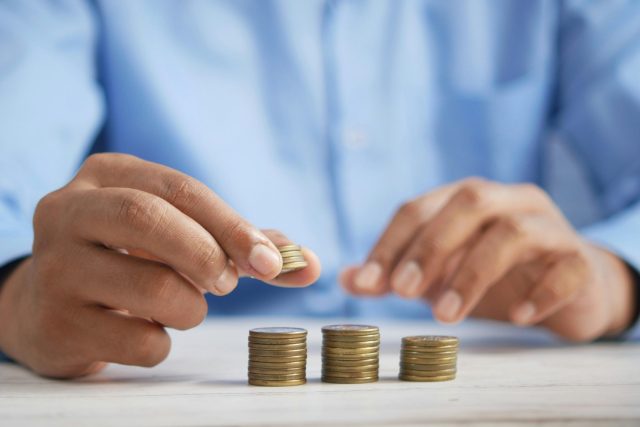 Picture of a person separating coins into three stacks representing tax, exemptions and net amount