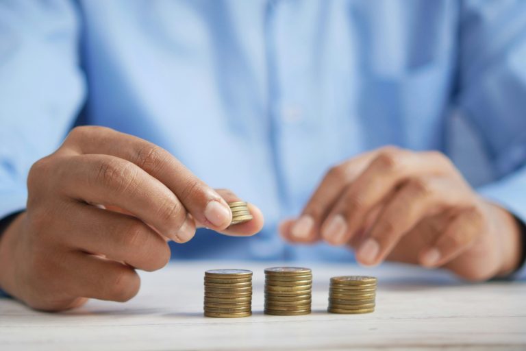Picture of a person separating coins into three stacks representing tax, exemptions and net amount