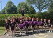 Legacy Cheer teams members wearing thier black uniform with purple pom poms. Members are aged between 5 and 10.