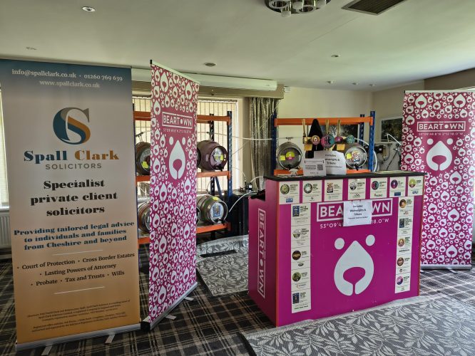 Beartown Brewery stand at Congleton Golf Club. The colours are magenta and white with a stylised face of a bear. Spall Clark pop up banner is next to it.